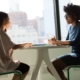 Two professionals seated in an office engaged in a job interview.